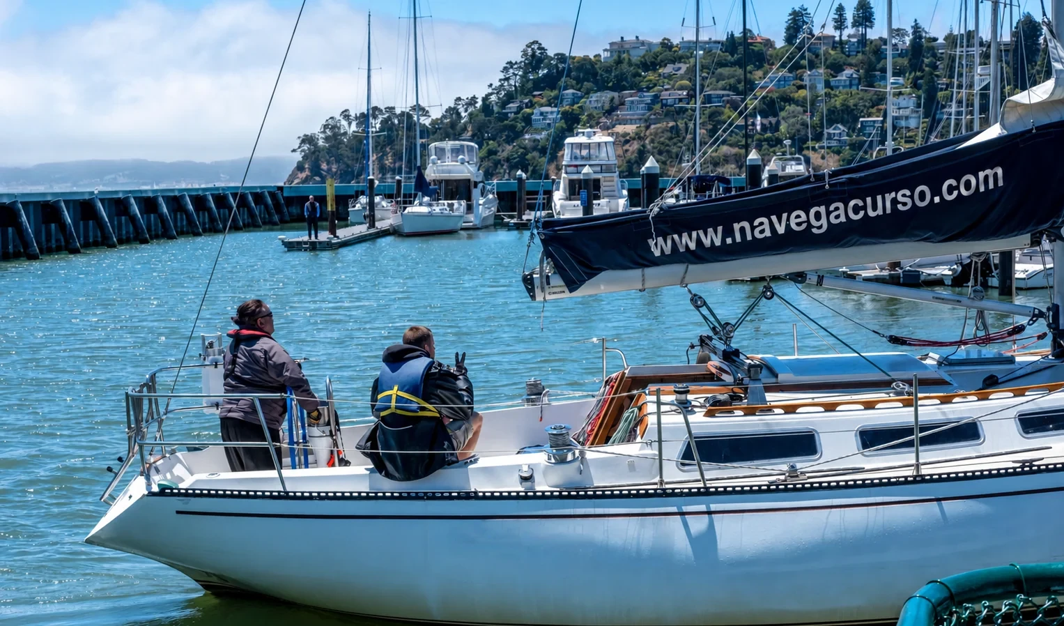 Dos personas a bordo de un velero amarrado en el puerto